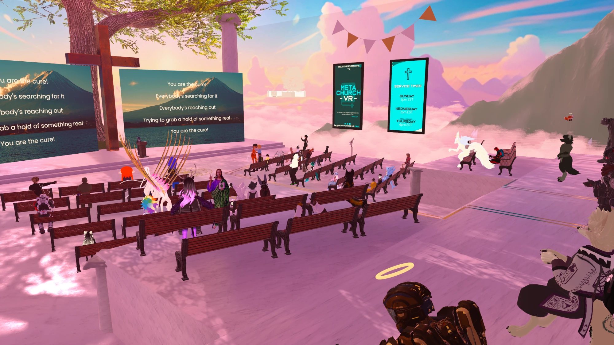 A live service under a pink sunset sky: many very different avatars sitting together in wooden pews, facing a wooden cross and screens showing worship lyrics.